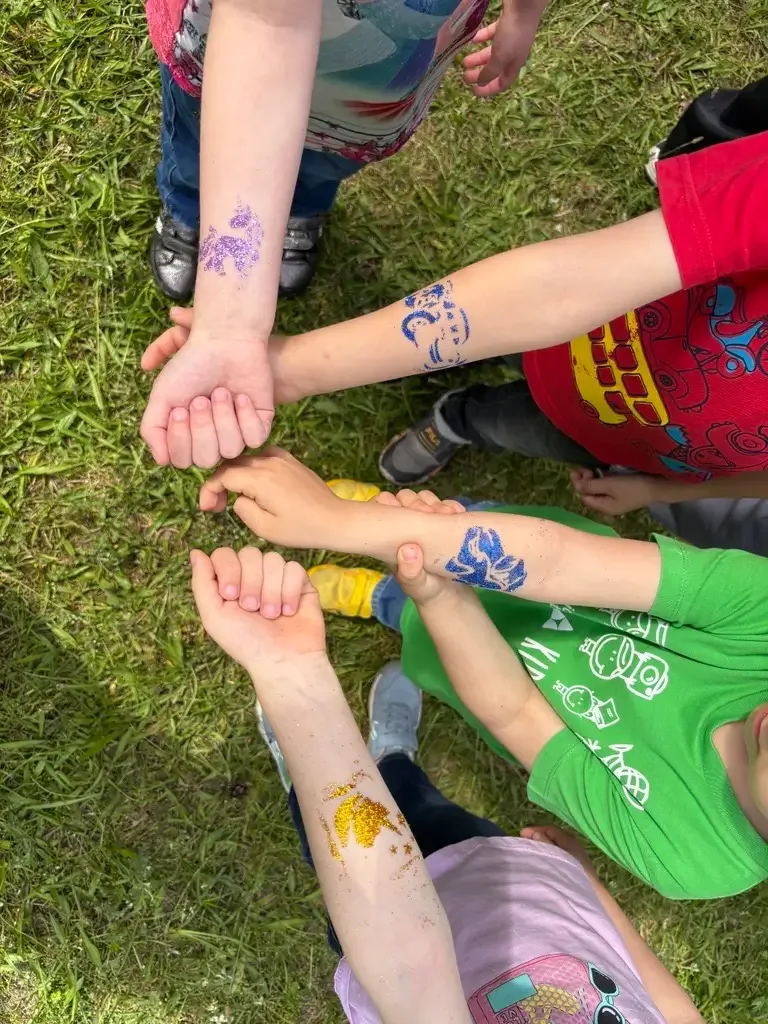 Дитячі руки з блискучими малюнками під час літнього свята.